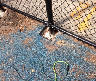Holes around fence can be filled with DIY playground surface repair.
