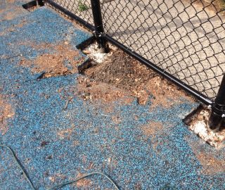 Holes in poured in around fence necessitate a playground surface hole repair.
