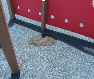 Playground surface damage prior to poured rubber repair.